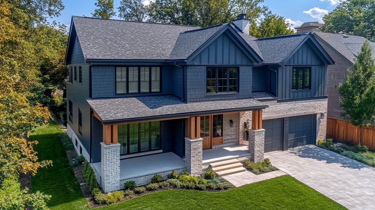 Two-story dark-blue house with stone accents, front porch, and landscaped lawn