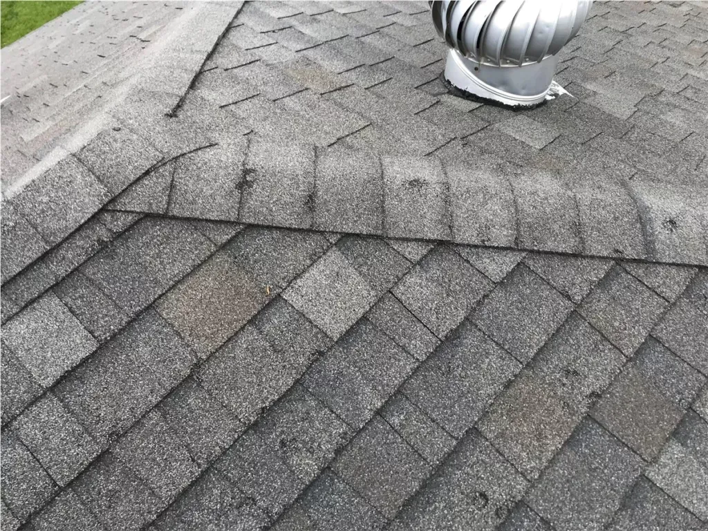 Close-up of a gray shingled roof with a silver vent pipe near the top right.