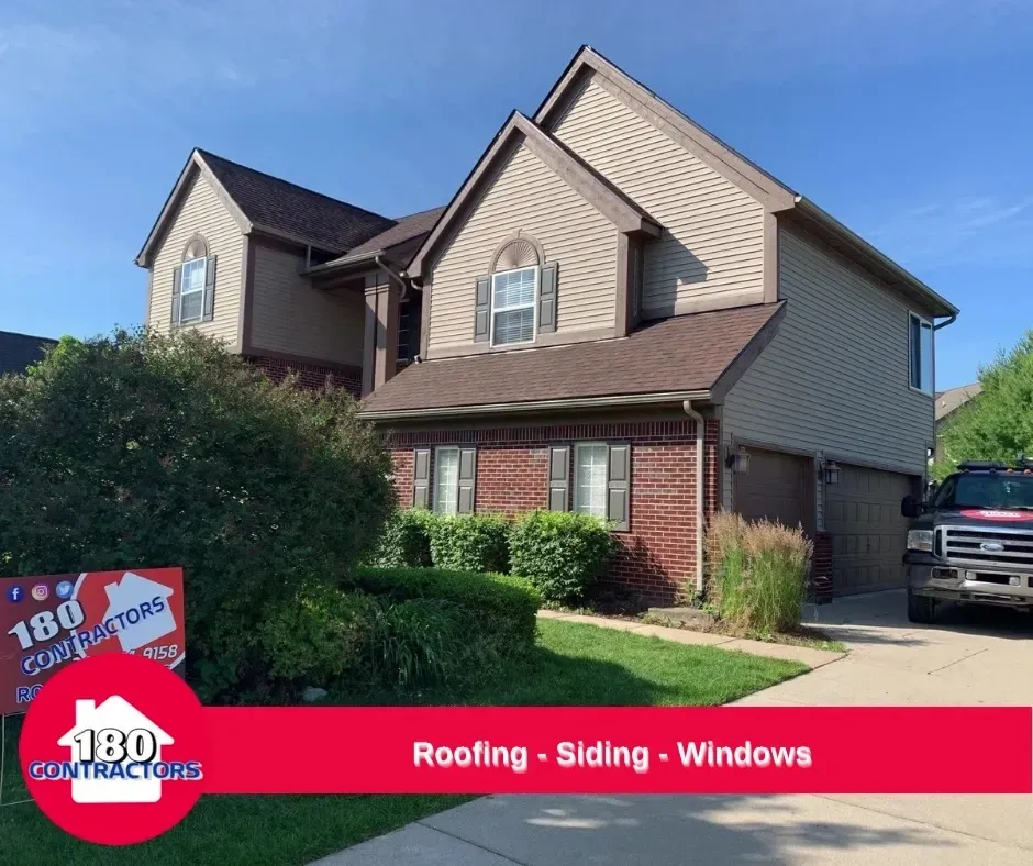 Suburban house with red roof and brick front, promoting roofing, siding and windows services.