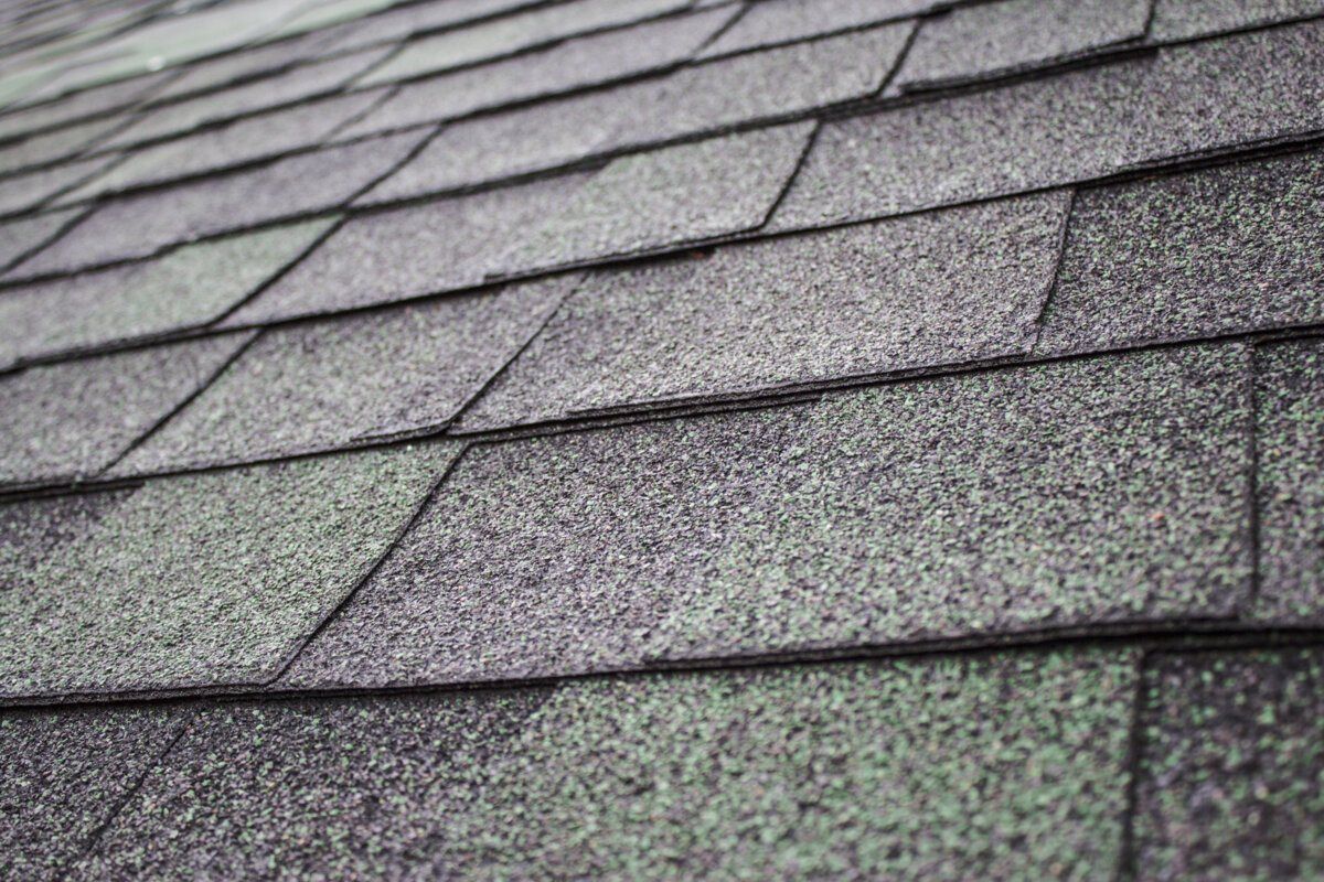 Close-up of gray asphalt roof shingles with a textured, weathered surface