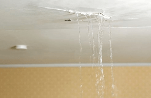Water leaking through a ceiling, dripping down into the room