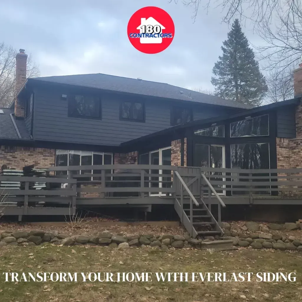 Two-story home with dark siding and stone accents, showcasing a new deck and railing under an Everlast Siding logo.