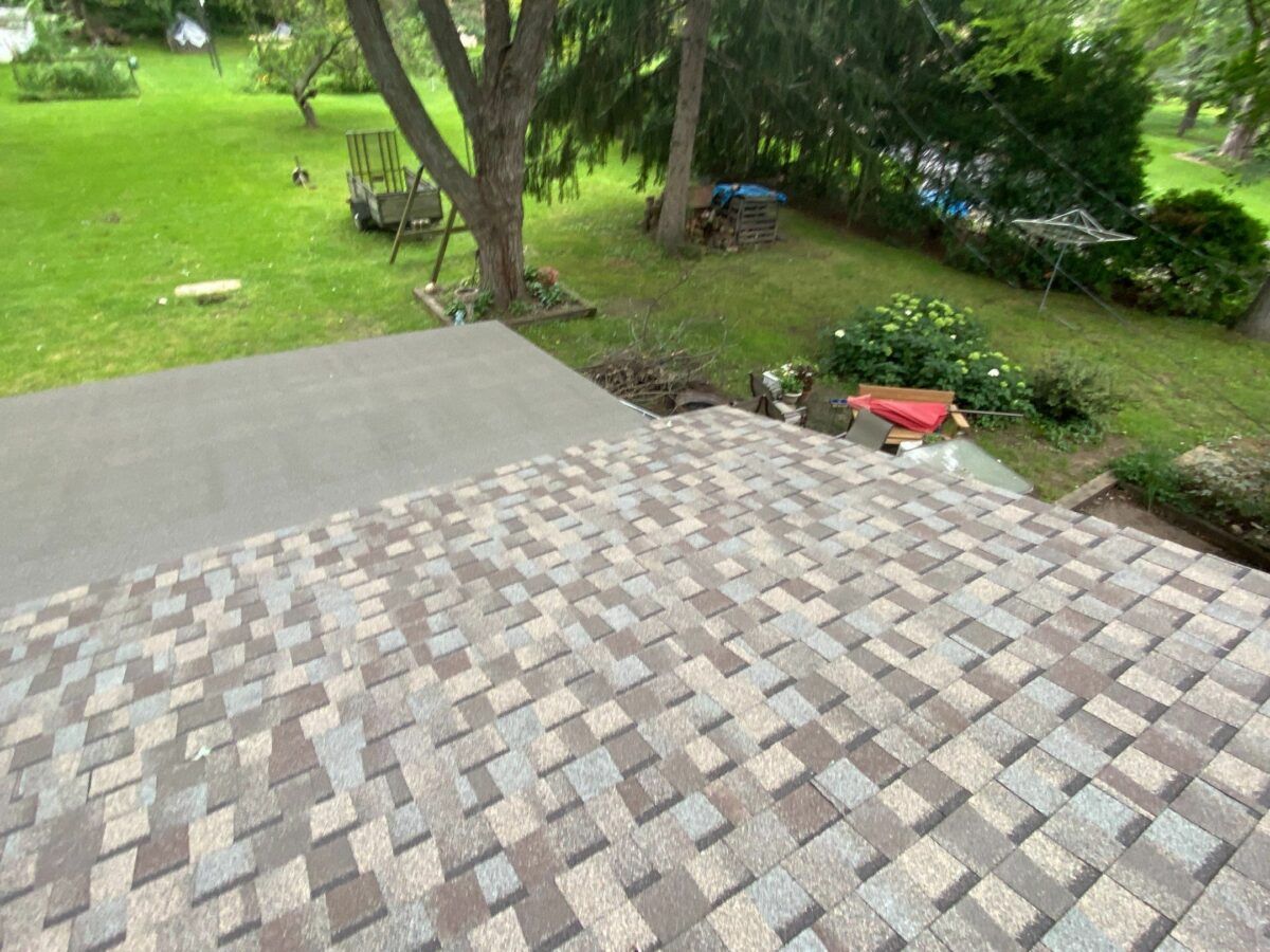 Stone patio beside a green lawn with trees and a small red bench in the background