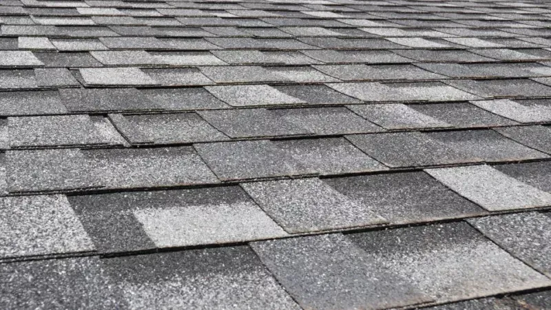 Close-up of gray asphalt roof shingles in overlapping rows, showing a textured rooftop surface.