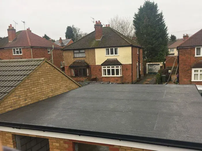 Flat black roof in front of brick houses in a suburban neighborhood