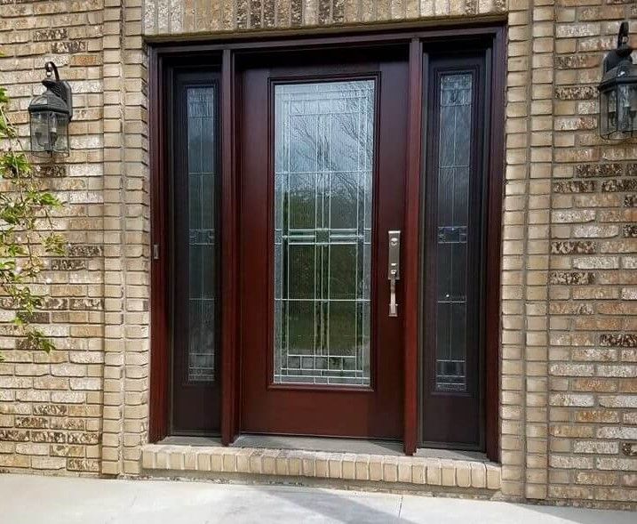 Front entrance with dark red double doors and sidelights set in a brick wall