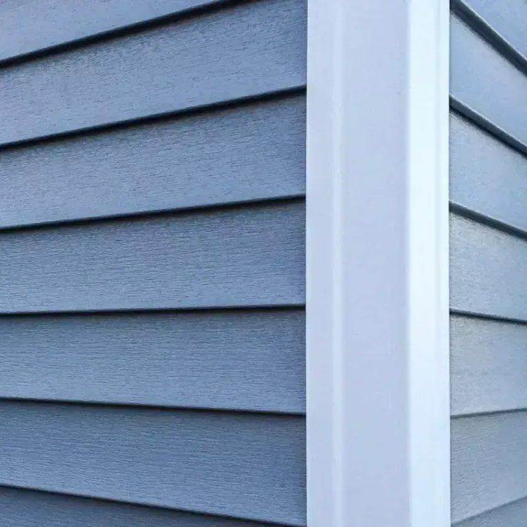 Blue-gray house siding with white corner trim and horizontal panel lines