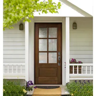 Front porch with a brown door, white siding, and potted flowers under a small roof.