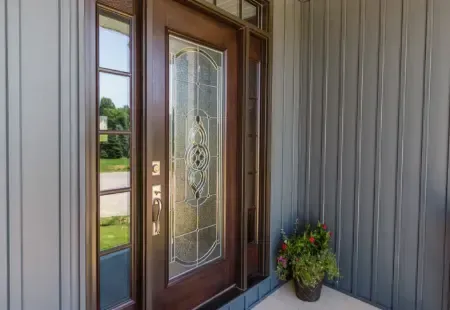 Front porch with a decorative glass front door, gray siding, and a potted plant.