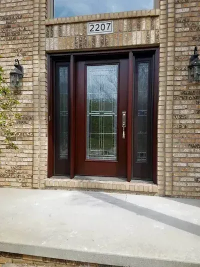 Front entrance of a brick house with a dark wood and glass double door, house number 2207 above.