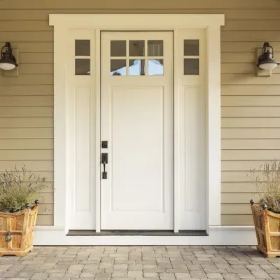 Front porch with white front door, sidelights, and potted plants on a beige house.