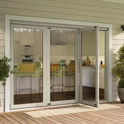 Open glass French doors to a bright kitchen with white cabinets and bar stools