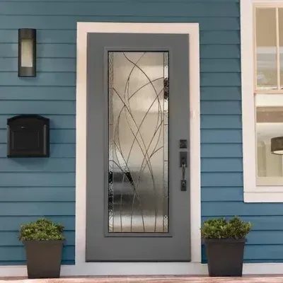 Blue house entry with gray door, frosted glass panel, wall light, mailbox, and potted plants