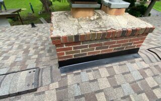 Brick planter with two metal vents on a paved walkway beside a path and bench