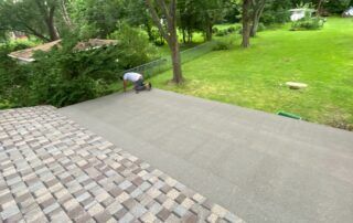 Stone patio beside a lush green lawn and garden with trees and shrubs.