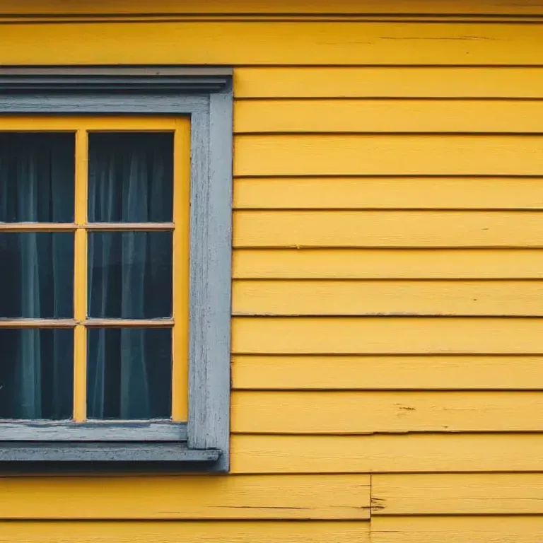 Blue-trimmed window on a yellow wooden siding wall