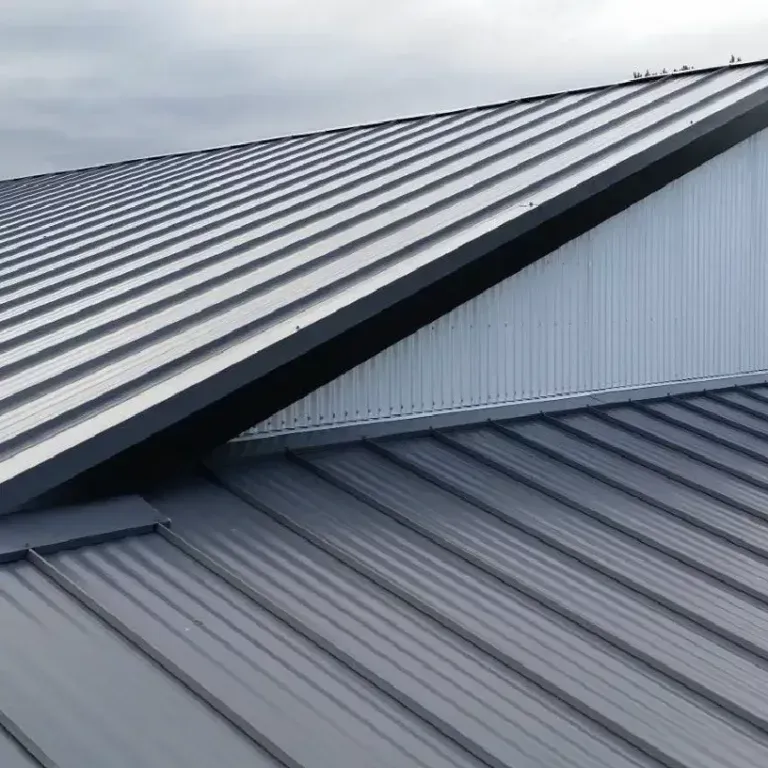 Gray metal roof with intersecting sloped sections and corrugated panels
