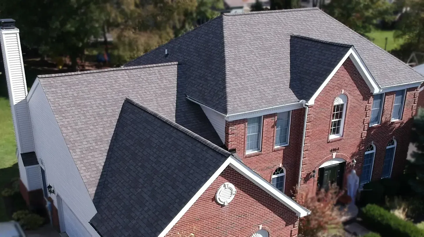 Aerial view of a red brick house with a gray shingled roof and white trim.