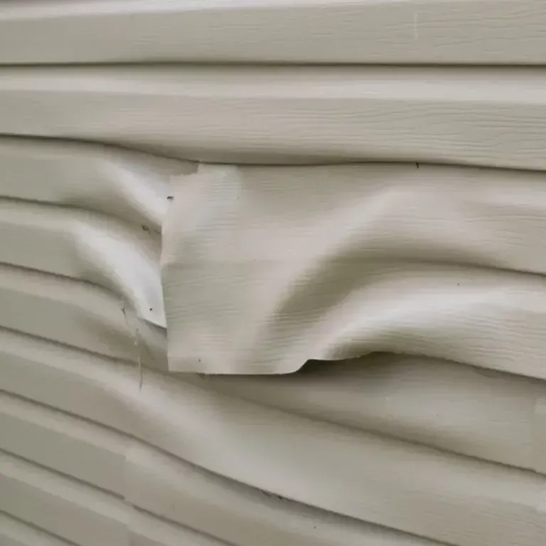 White vinyl siding with a dented, wrinkled section and small screw holes