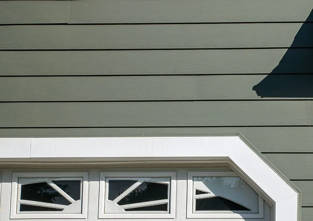House siding with a white-trimmed row of small windows beneath a roof overhang