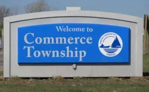 Welcome to Commerce Township sign on a blue and white roadside monument