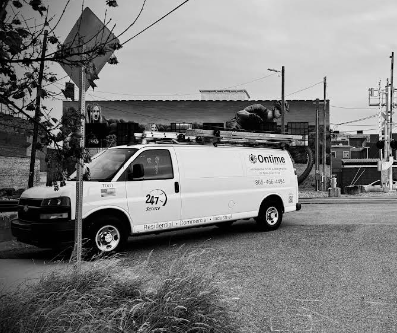White service van parked on a street beside a building and utility poles in black-and-white scene