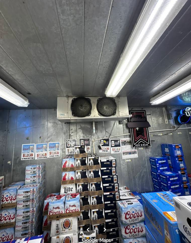 Convenience store aisle with stacked snack and drink displays under bright fluorescent lights.