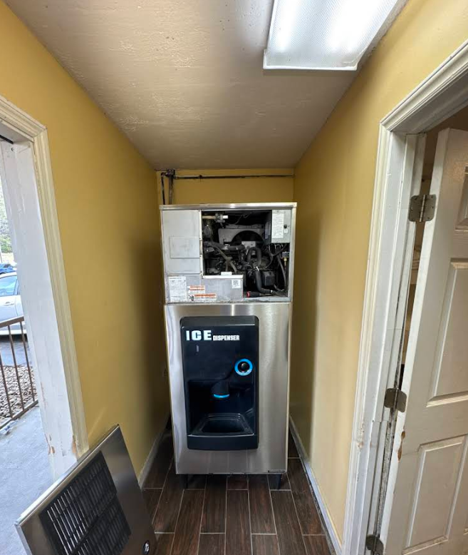 Laundry room with a front-loading washer and dryer stacked in a narrow yellow hallway