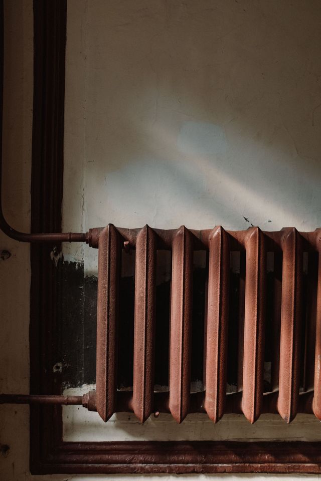 Rusty old radiator against a wall in a dim interior corner