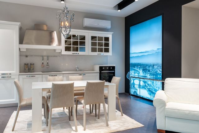 Modern dining room with white table, chairs, dark walls, and a large blue wall display.
