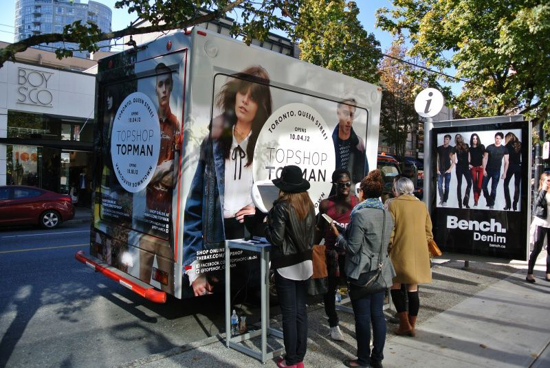 A group of people standing in front of a topshop truck