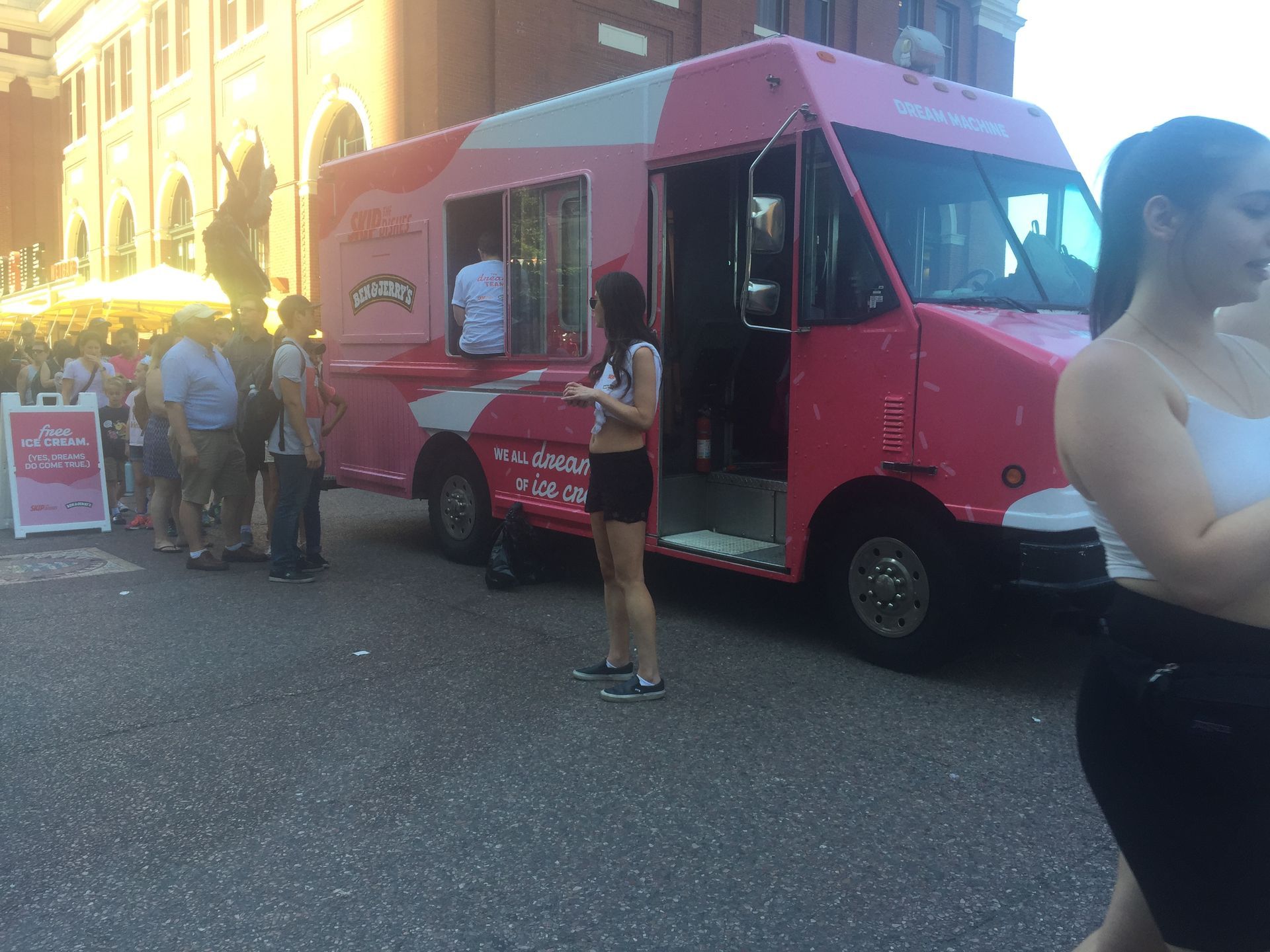 A woman is standing in front of a pink food truck