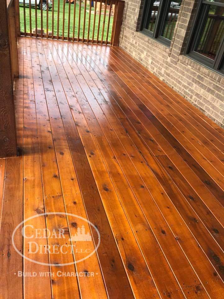 A wooden deck with a brick building in the background