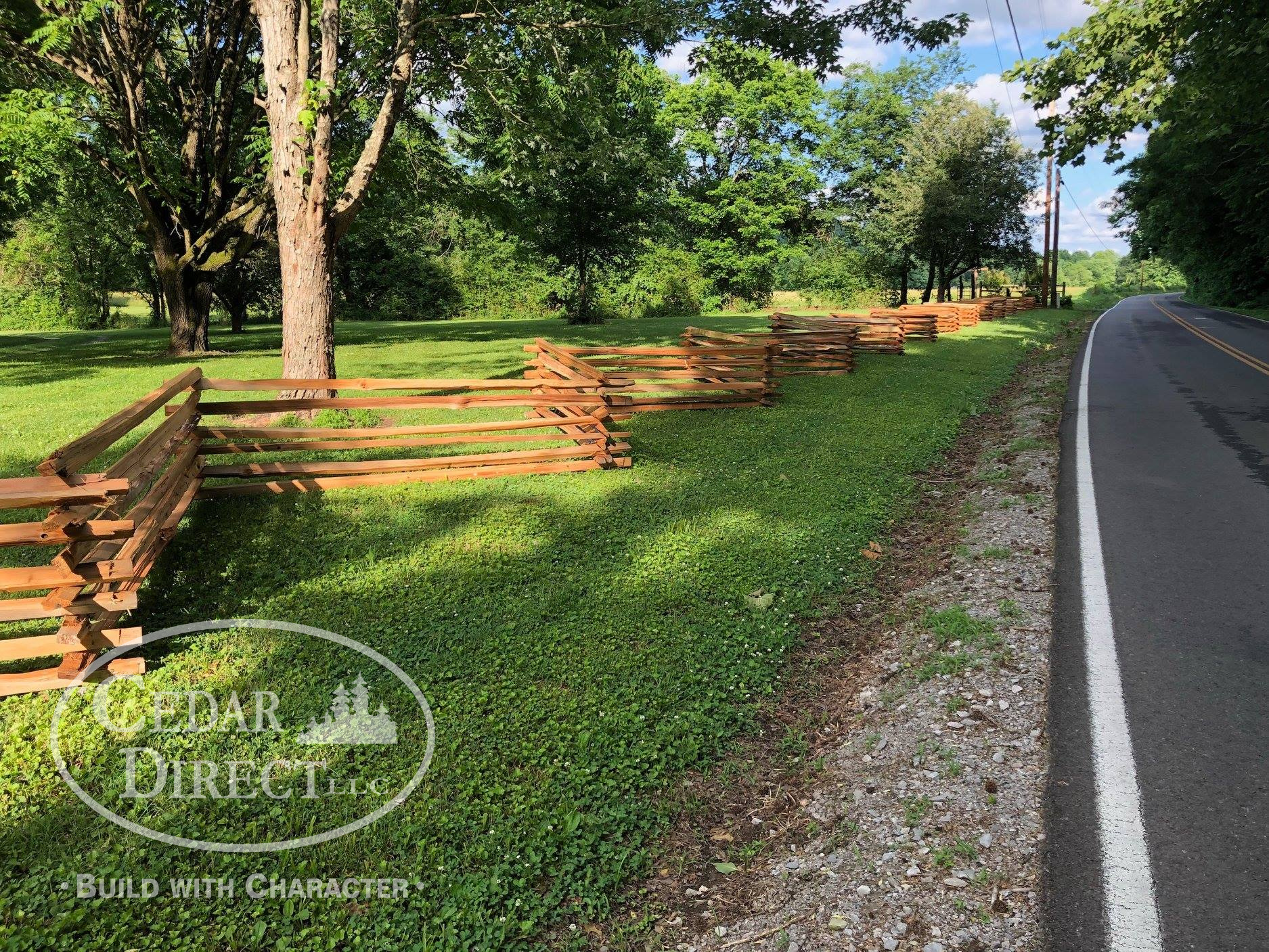 A wooden fence is along the side of a road.