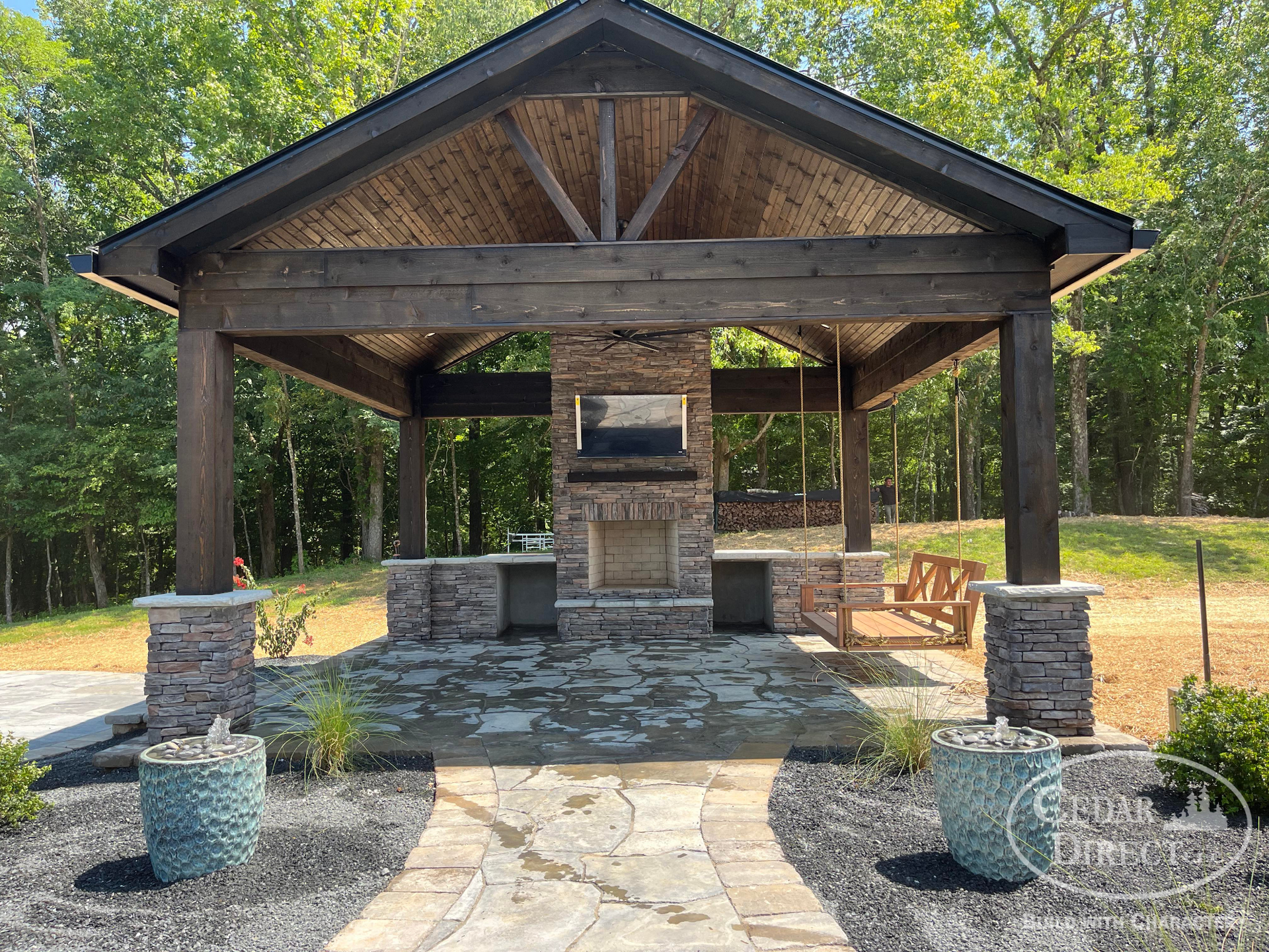 A large wooden pavilion with a fireplace in the middle of it.