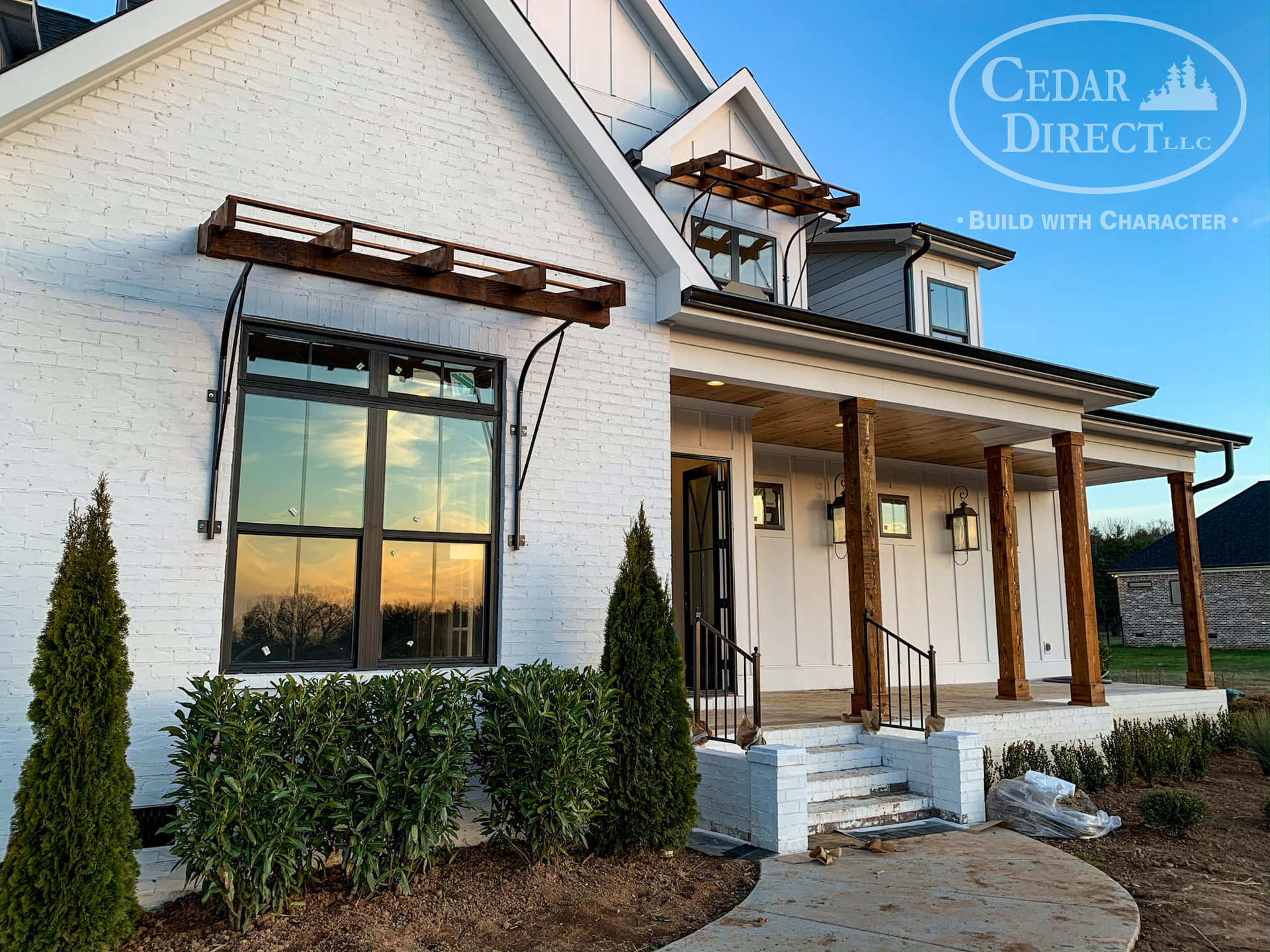 A white house with a porch and a sign that says cedar direct