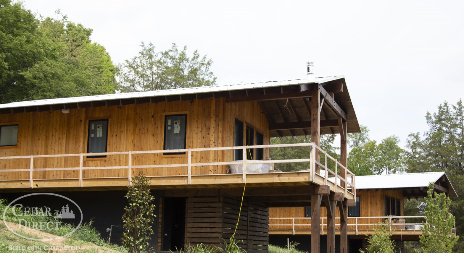A large wooden house with a balcony and trees in the background