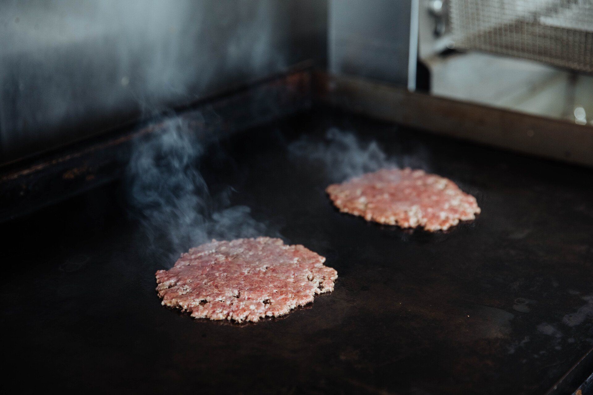 Denver's best burger searing on a flattop grill