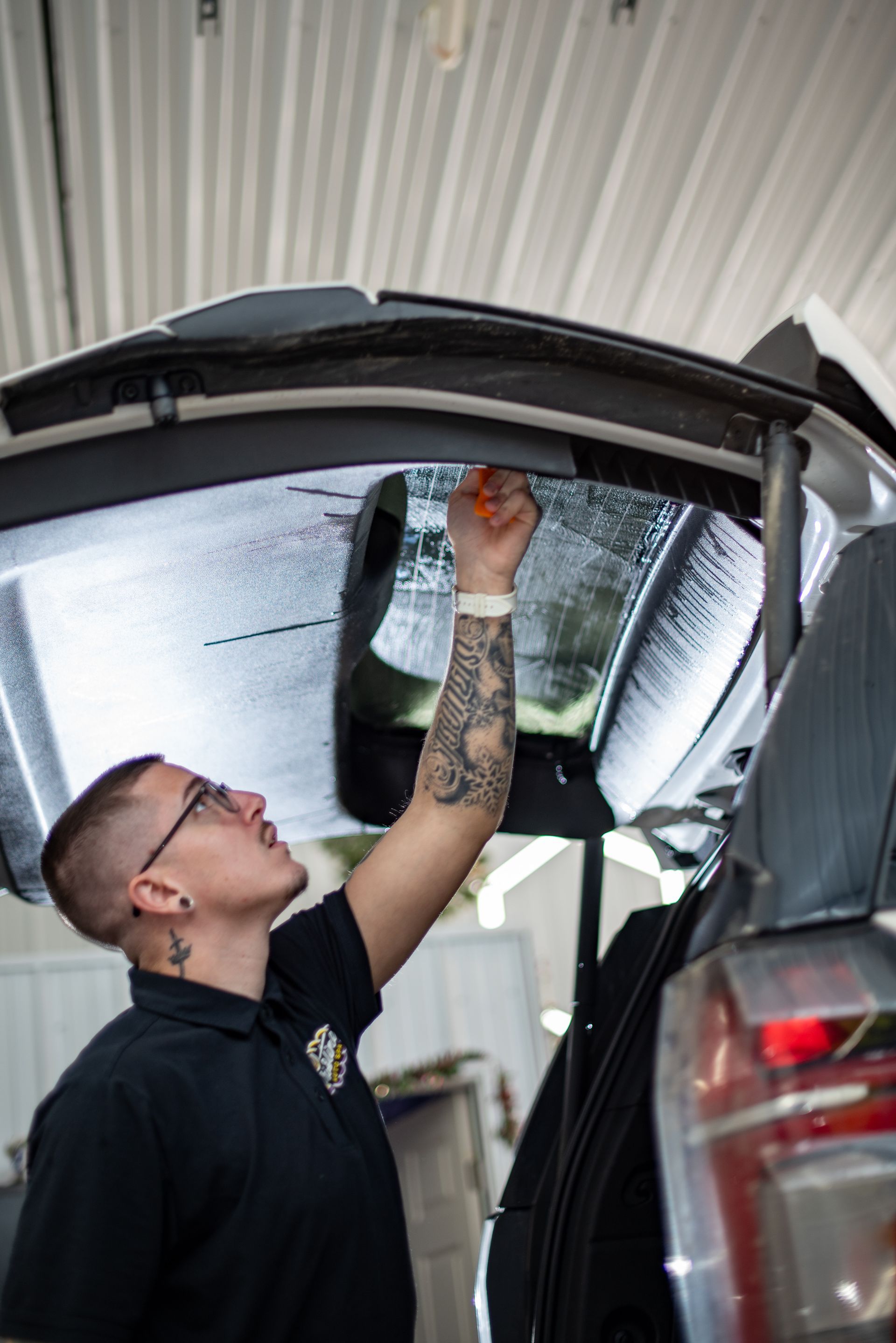 Person with tattoos installing tint on car window.