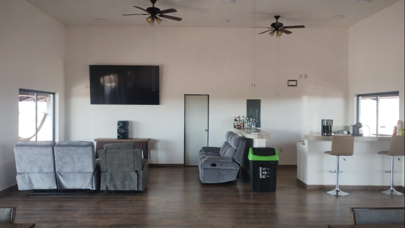 Spacious modern living room with sofa, recliner, wall-mounted TV, ceiling fans, and bar seating