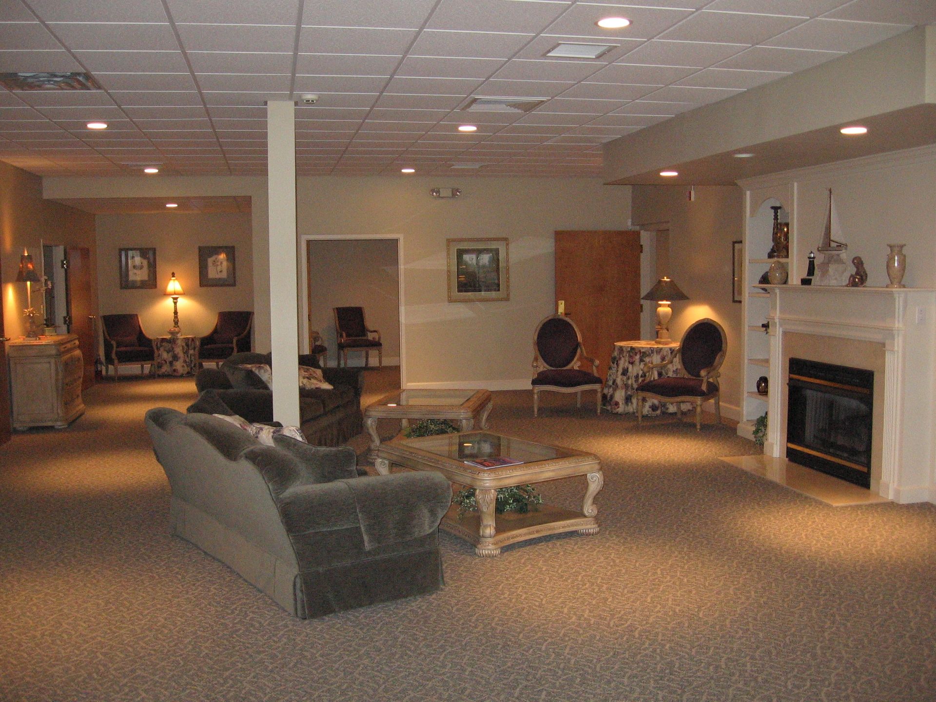 A spacious room with sofas, chairs, fireplace, and soft lighting; likely a waiting or reception area.