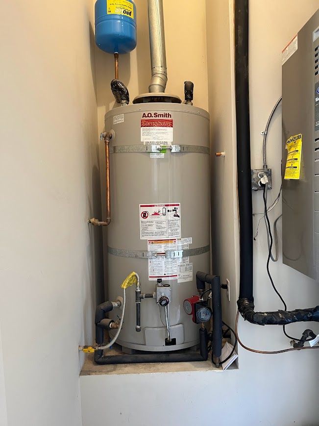 A water heater is sitting in a corner of a room next to a wall.