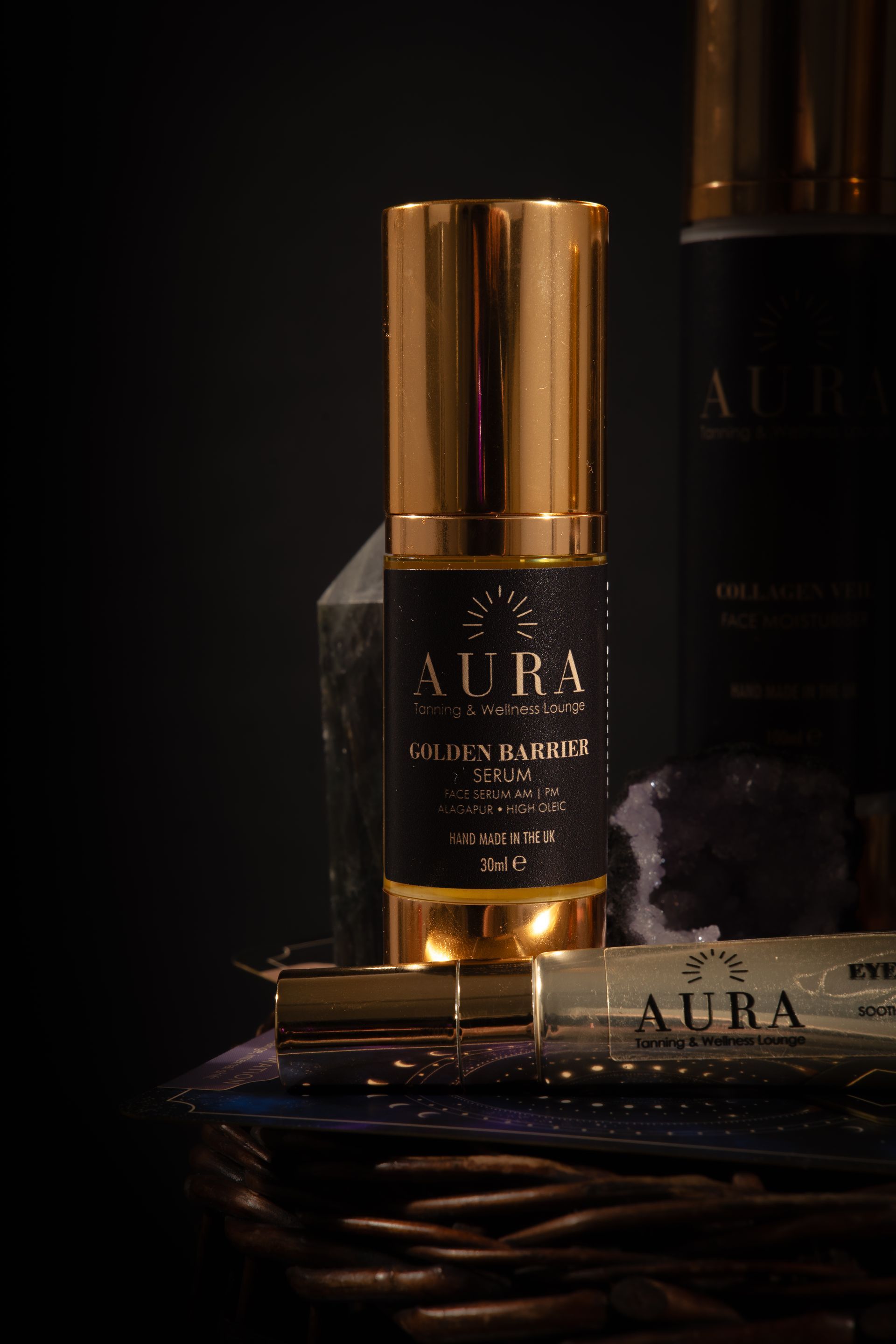 Luxury AURA skincare bottle with gold cap and warm amber glow on a dark background