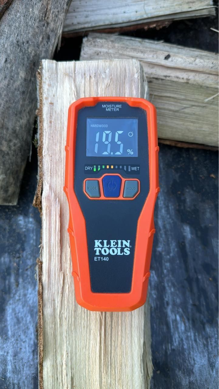 Orange digital thermometer on a wooden beam outdoors, reading 79.5°F.
