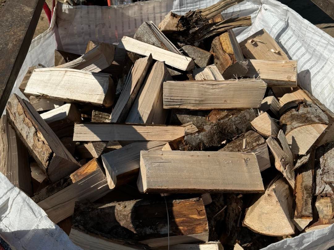 A pile of cut firewood logs stacked in a wooden bin outdoors.