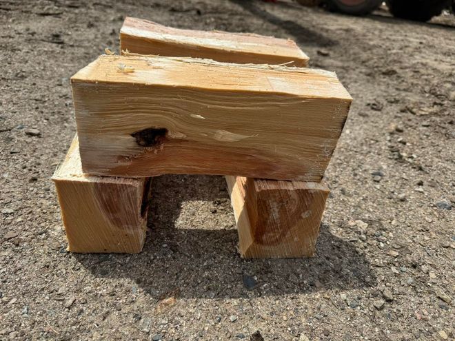 Small wooden block toy animal with four legs, sitting on sandy ground.
