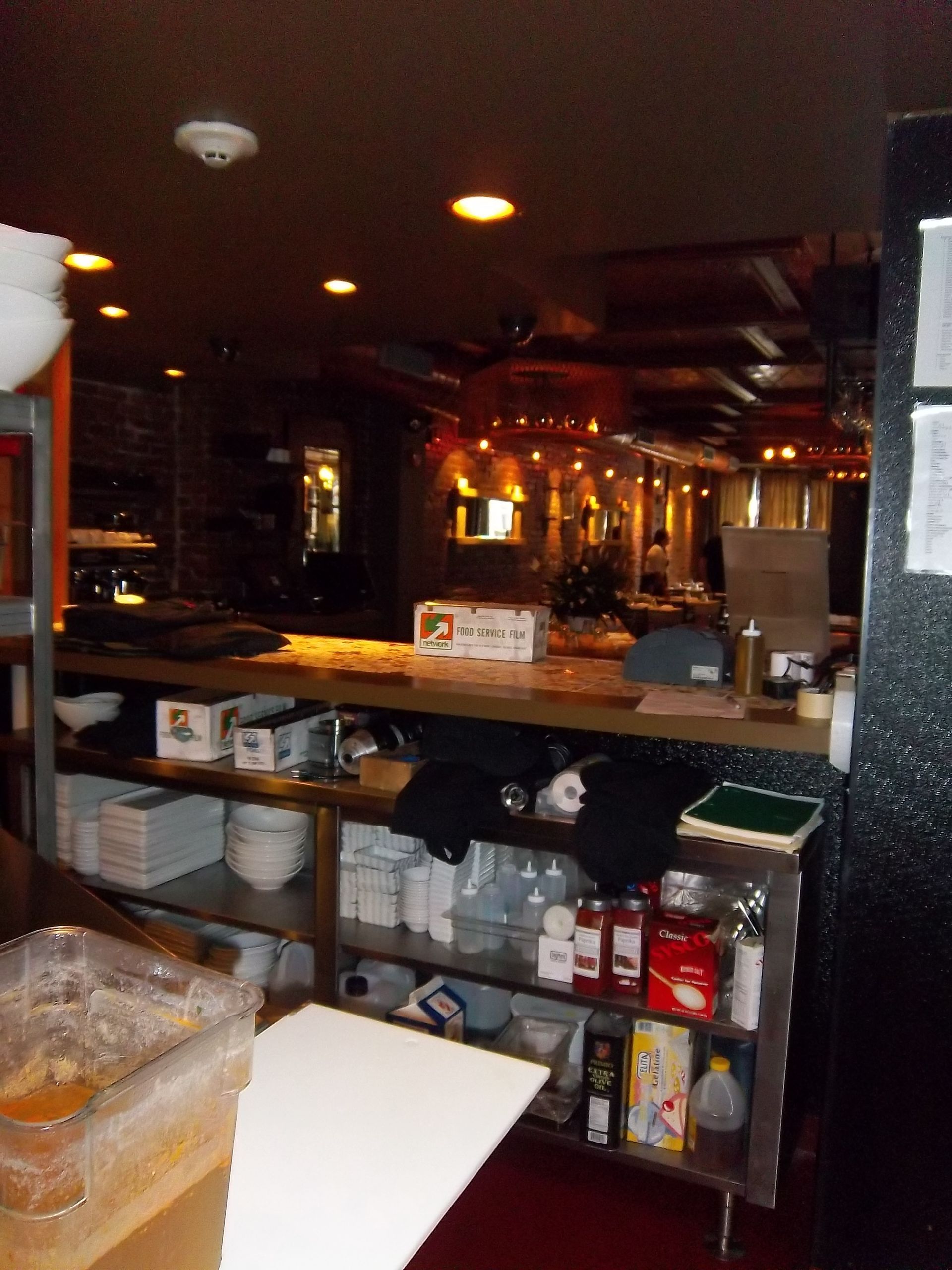 An indoor view of a restaurant service counter with shelves holding organized dishware, supplies, and containers.