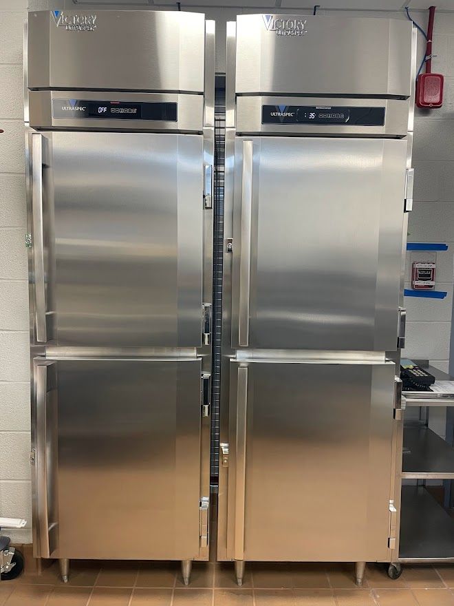 Two stainless steel, side-by-side commercial refrigerators in a kitchen setting.