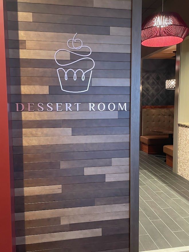 A wooden wall sign with a white cupcake outline and the text 