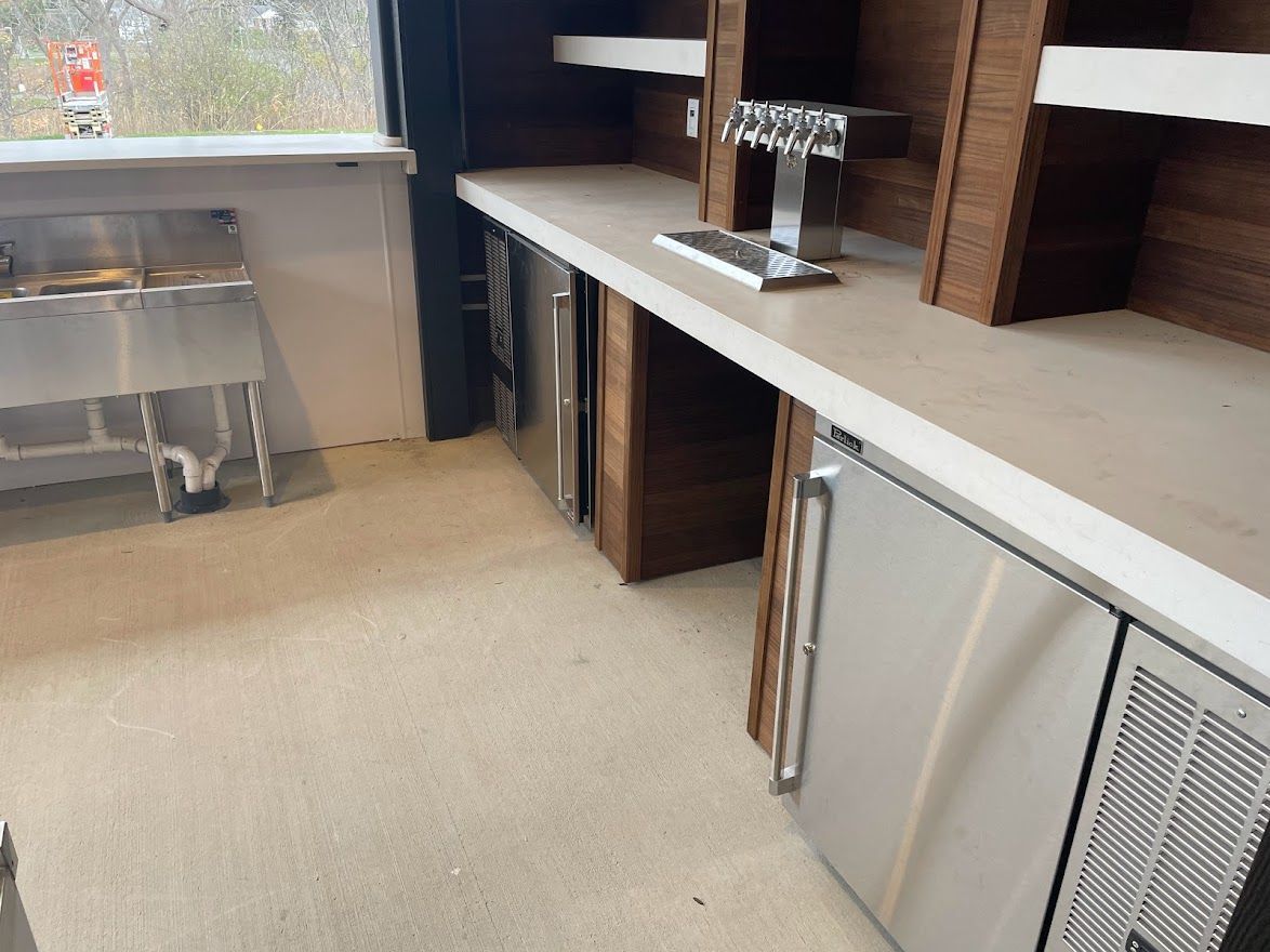 A bar area featuring a stainless steel sink, a beer tap, and two under-counter stainless steel refrigerators.